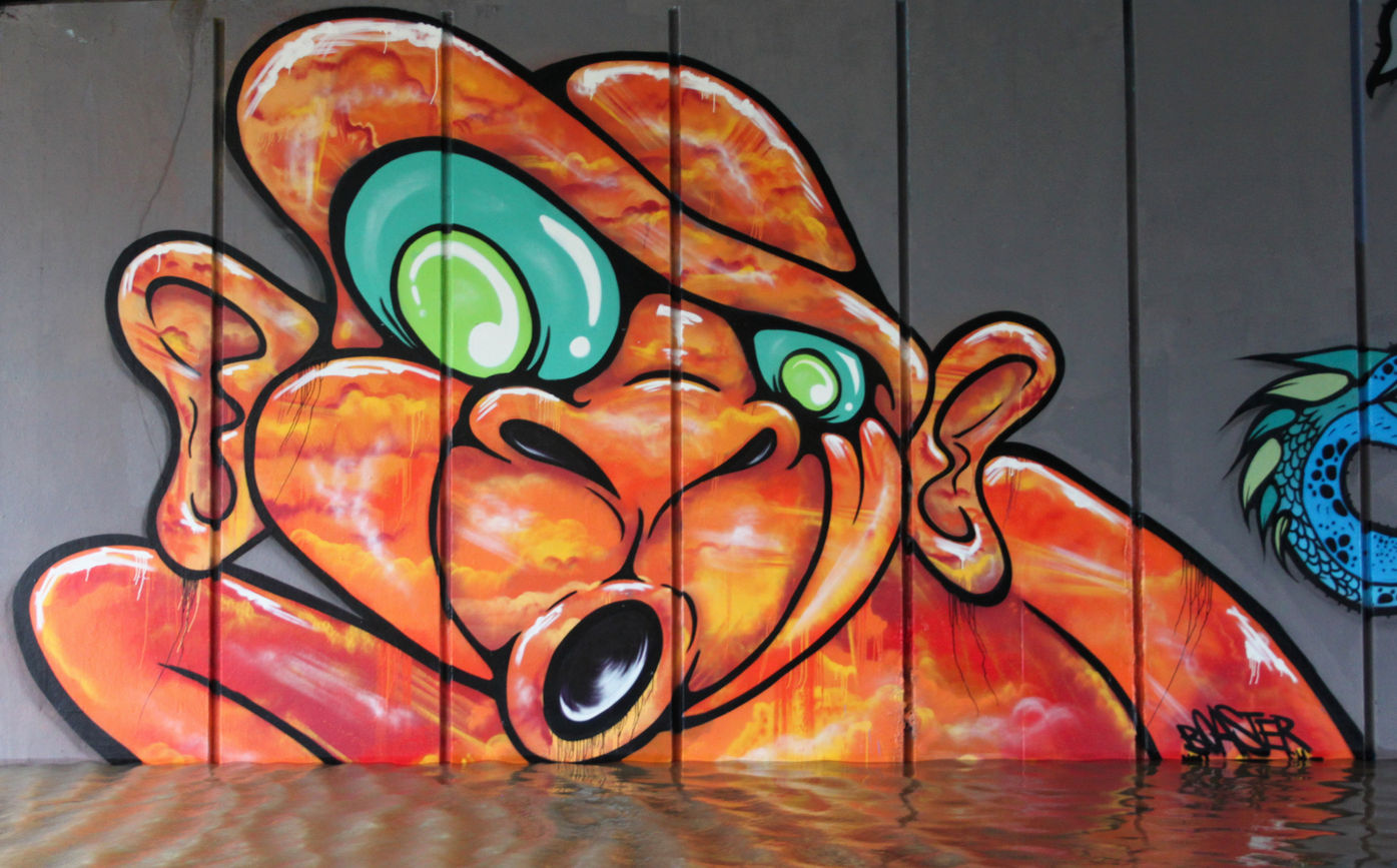An orange graffiti character in a flooded tunnel