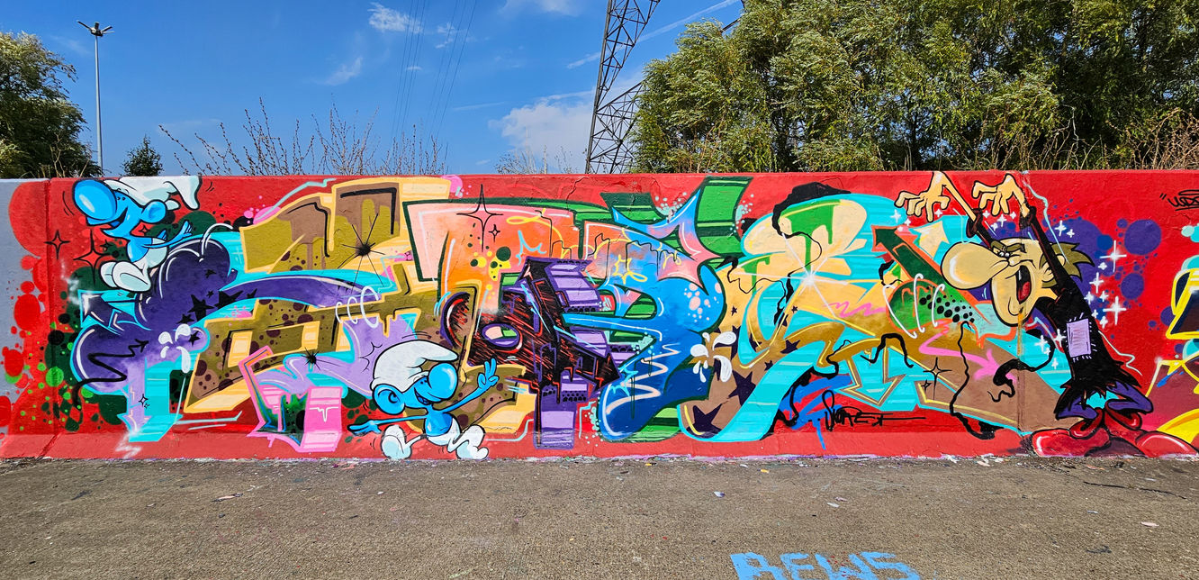 Colourful graffiti letters spray painted on a wall featuring cartoon characters of The Smurfs