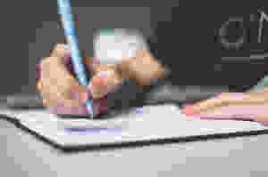 hands holding a pen over a notebook