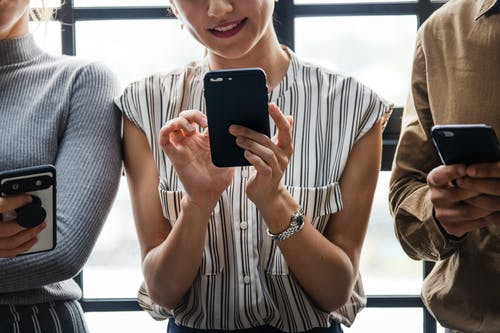 Three people looking at their cell phones