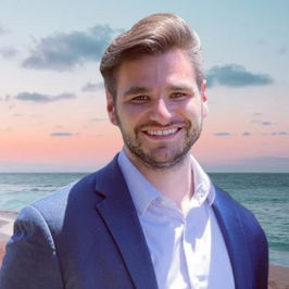 Kevin Wozniak, Travel Designer, Romantics Travel team member standing beside the ocean at sunset.