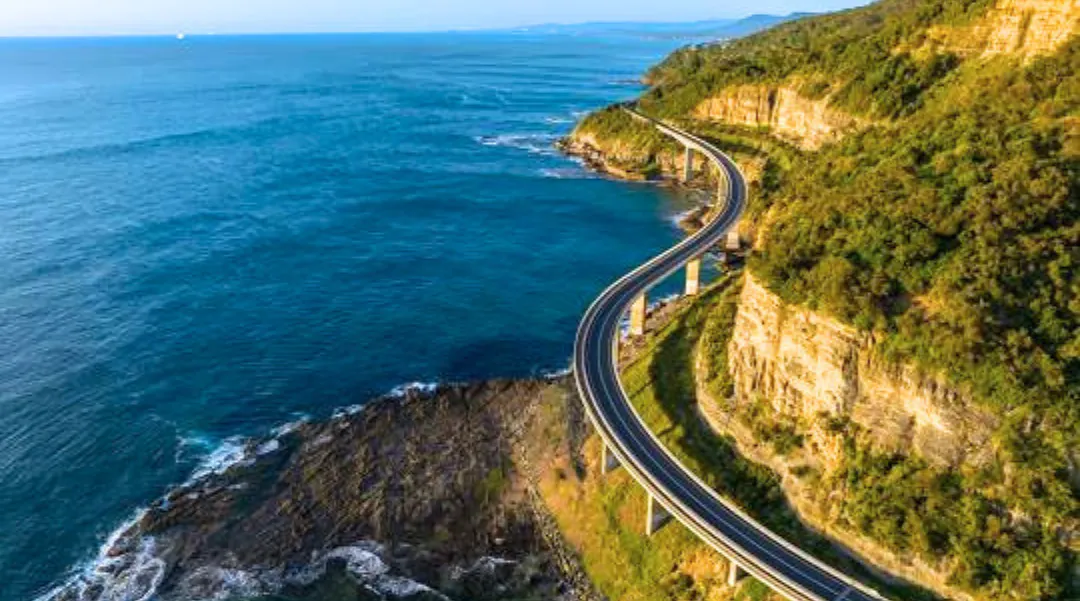 A scenic coastal road winding along cliffs with stunning ocean views, representing travel and exploration.
