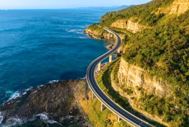 A scenic coastal road winding along cliffs with stunning ocean views, representing travel and exploration.