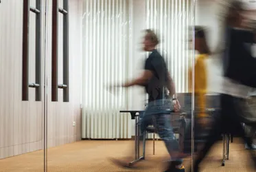 Blurred motion of people walking in an office corridor, symbolizing business activity and collaboration.