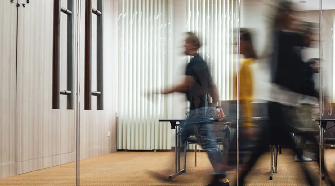 Blurred motion of people walking in an office corridor, symbolizing business activity and collaboration.