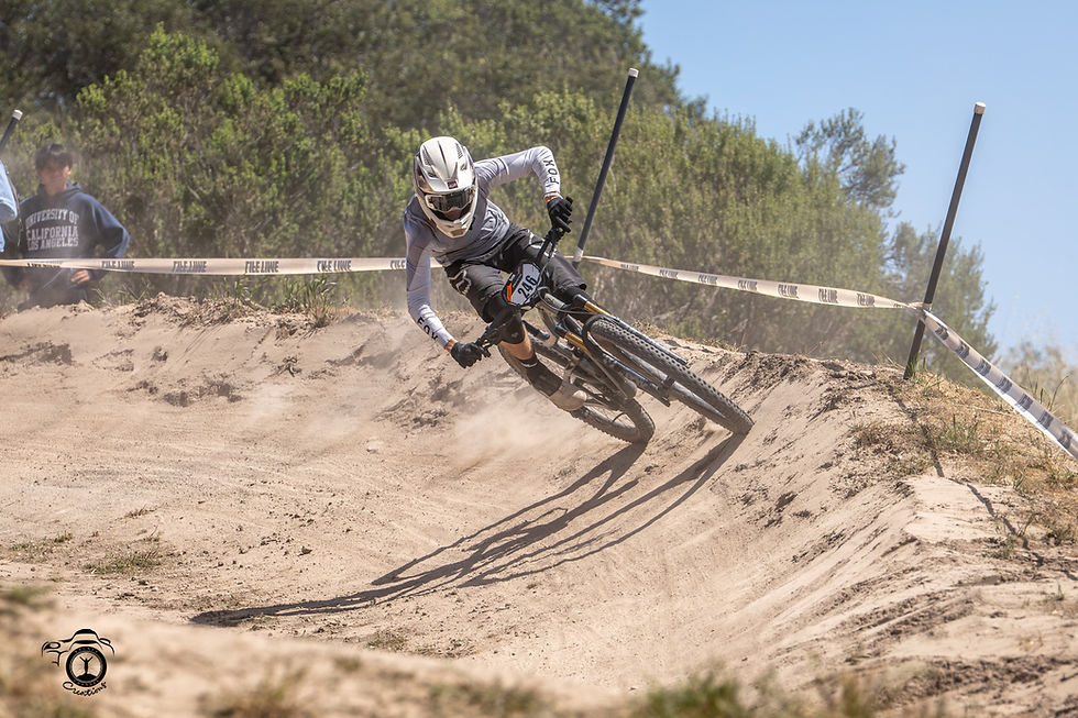 Downhill mountain biker carving a dusty berm turn at Sea Otter Classic 2026 in California, photographed by Alexei Bautin