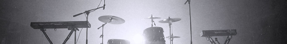 Drum kit under stage lights representing original songs, creative expression, and the stories behind the music.