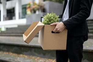 A gentleman leaves work taking his box of desk items