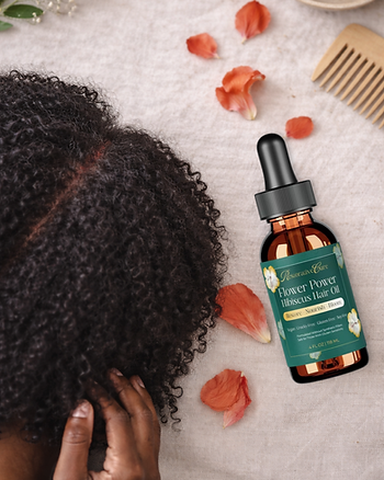 Flat lay wellness blog cover image showing a close-up of an African American woman’s curly hair with mild scalp redness indicating inflammation, styled on a warm linen background. The Restorative Care Flower Power Hibiscus Hair Oil bottle sits beside her hair, surrounded by soft hibiscus petals and a wooden comb, representing gentle, inflammation-supportive scalp care.