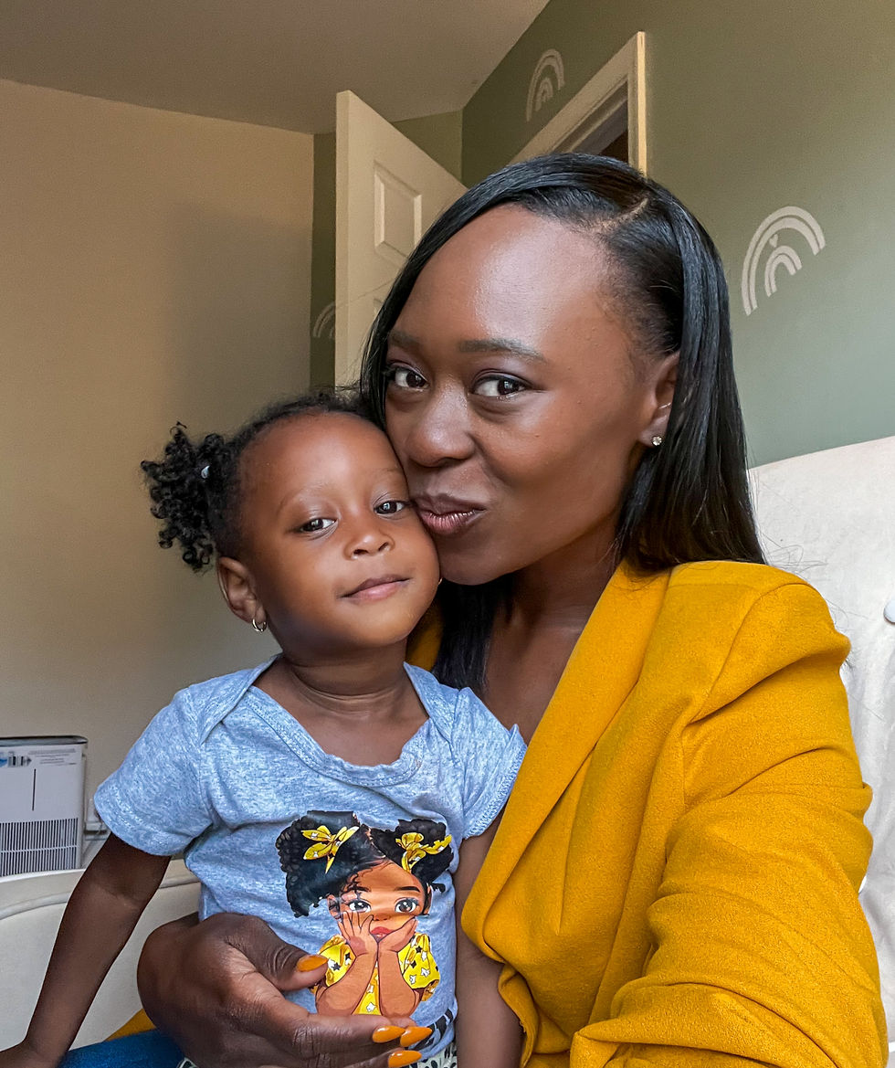 Tatiana Holmes smiling and holding her young daughter, sharing a warm mother-daughter moment. Tatiana wears a mustard yellow blazer while her daughter wears a gray shirt with a cartoon girl design. The image reflects family, legacy, and the heart behind Kingdom entrepreneurship.