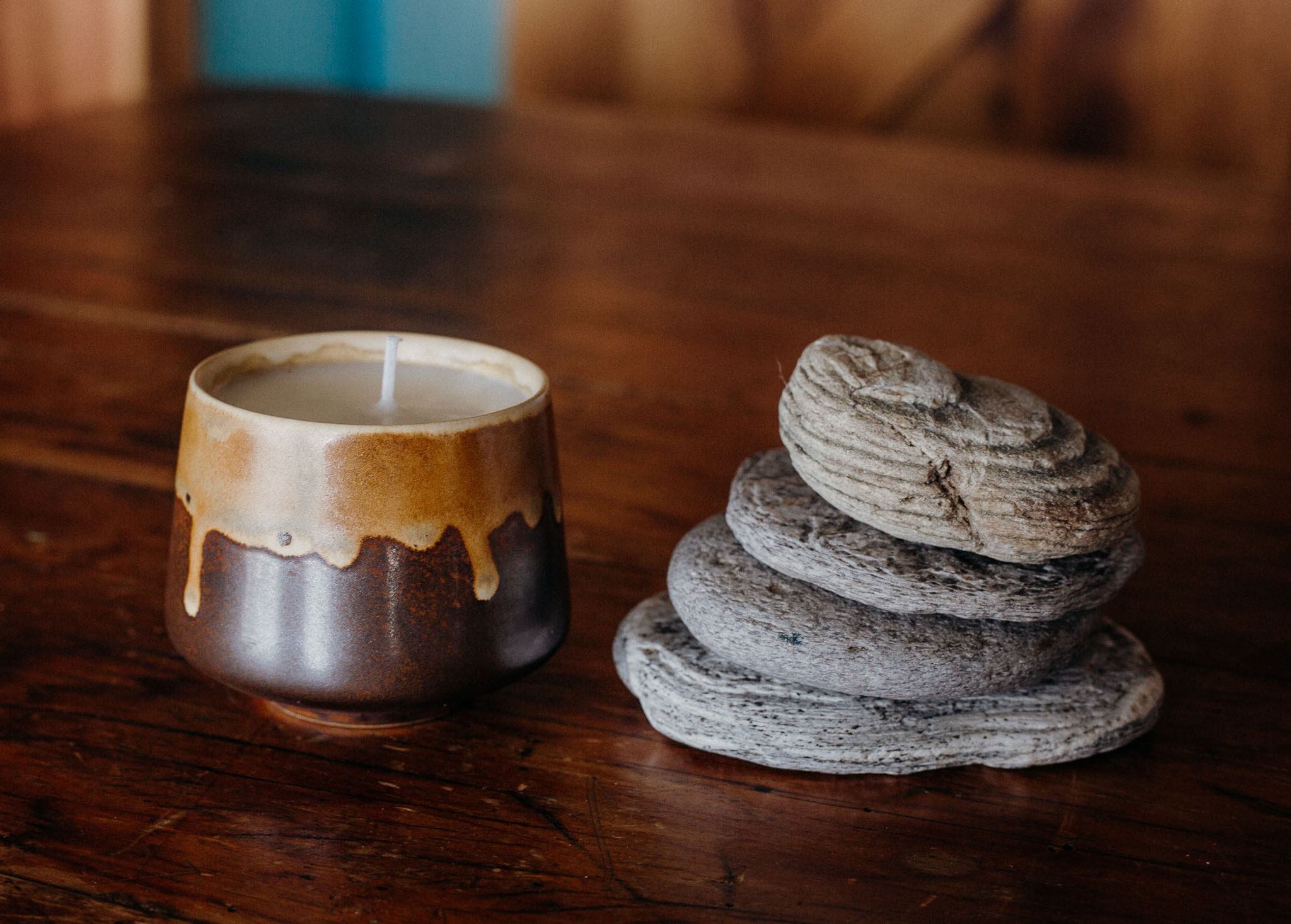 drip patterned glazed candle jar with soy wax next to stacked stones