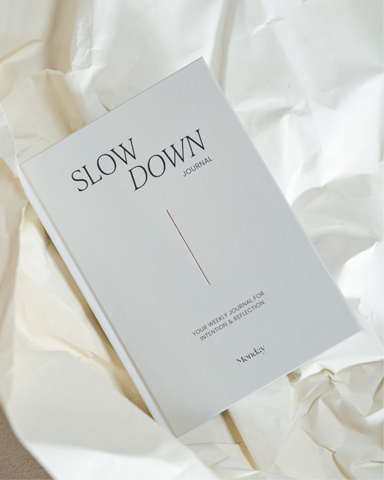 white covered journal with words slow down