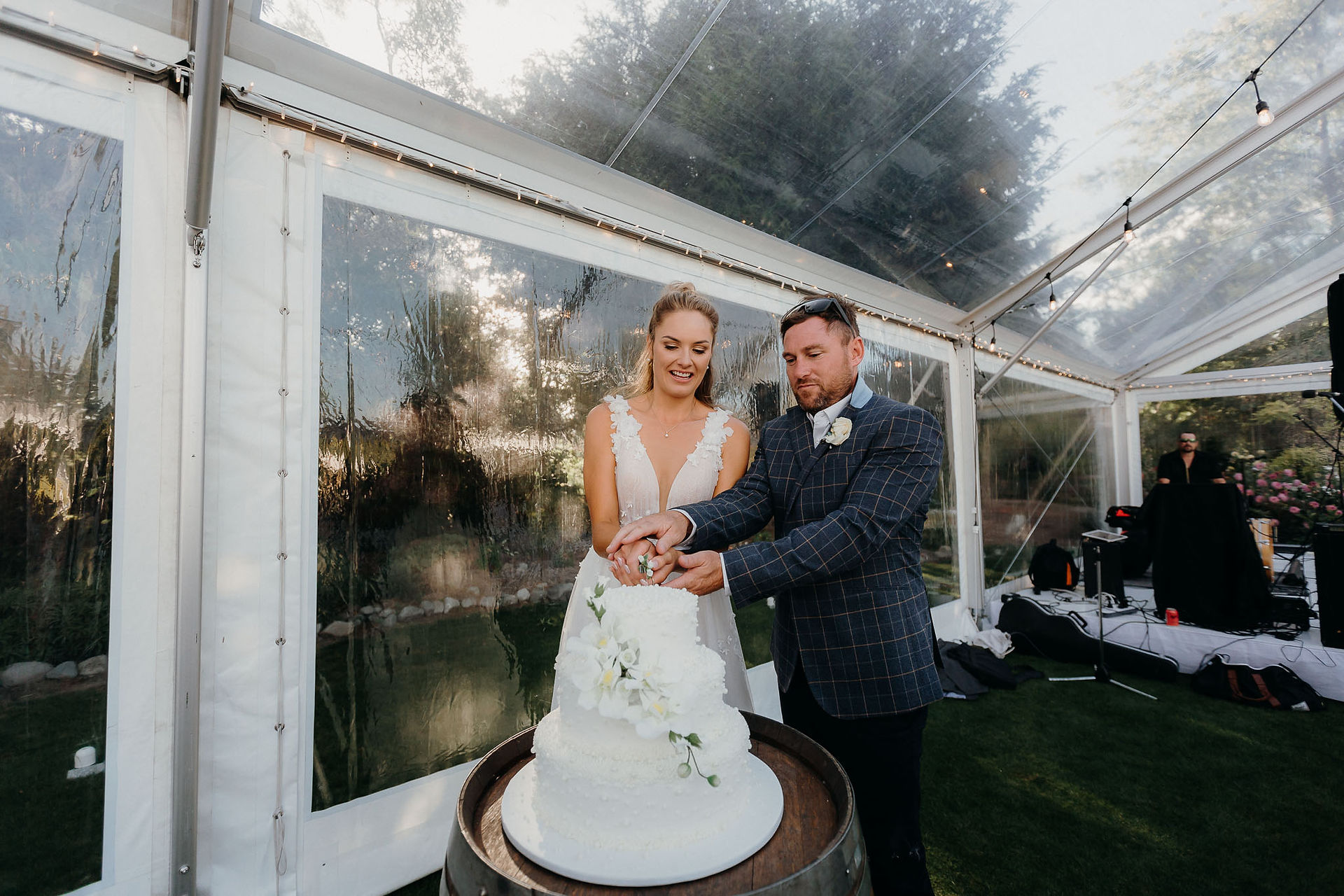 bride and groom cut white wedding cake with floral details at a Canterbury wedding reception