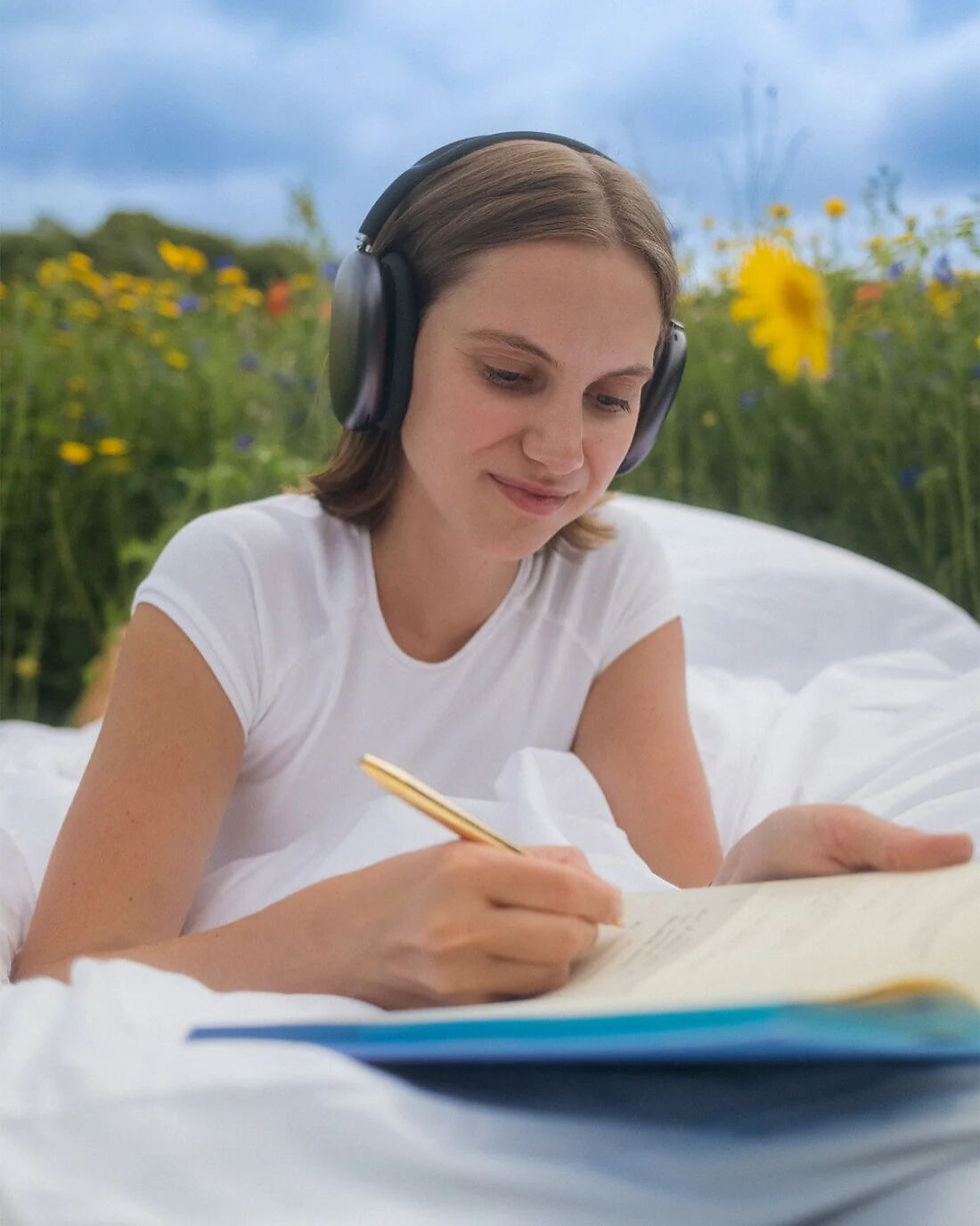 Thumbnail: woman writing in blue purple cover of new calm five minute journal