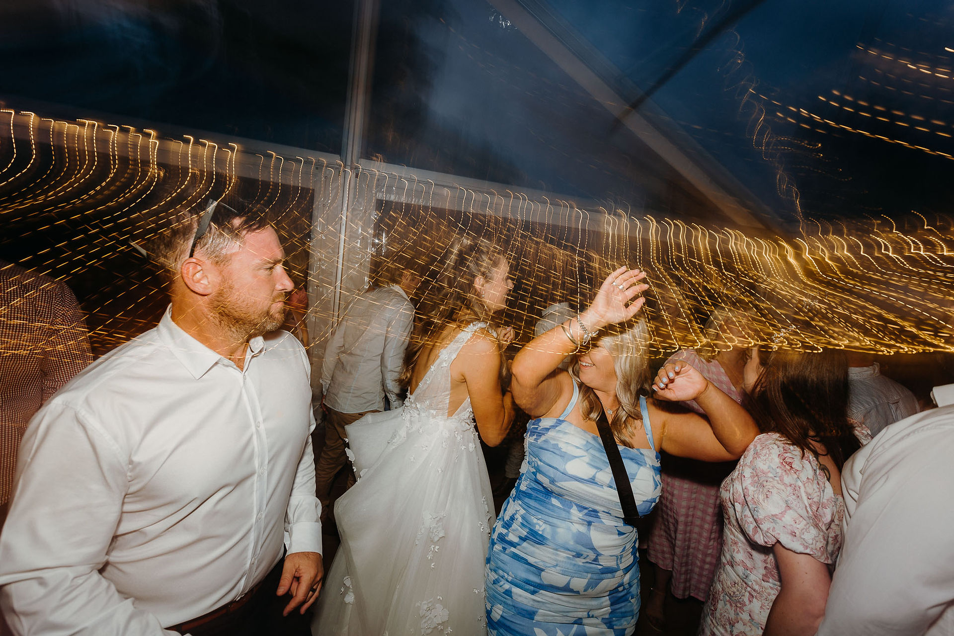 Wedding guests dancing beneath a clear marquee in Canterbury