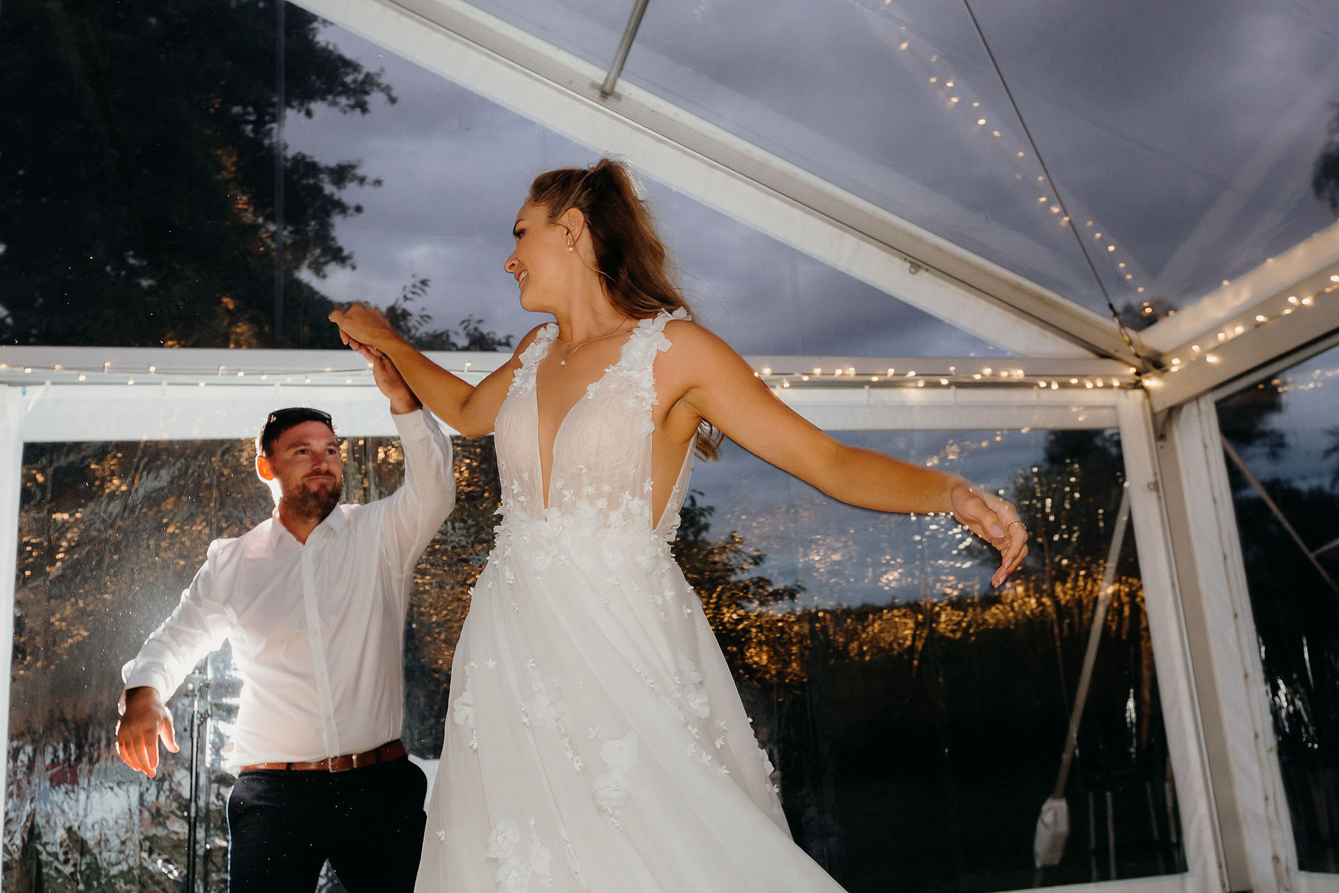 Bride and groom sharing their first dance beneath a clear marquee