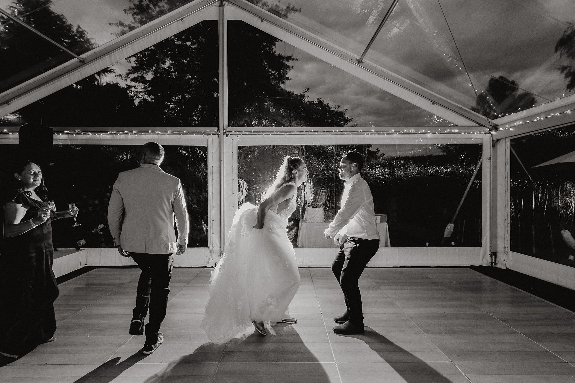 Bride and groom sharing their first dance beneath a clear marquee