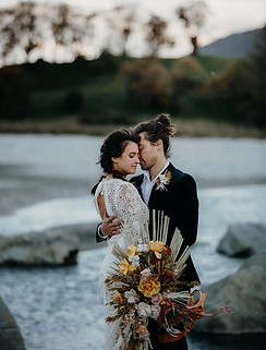 bride and group having a quiet moment against a pictureque landscape of a riverbed with hills and trees