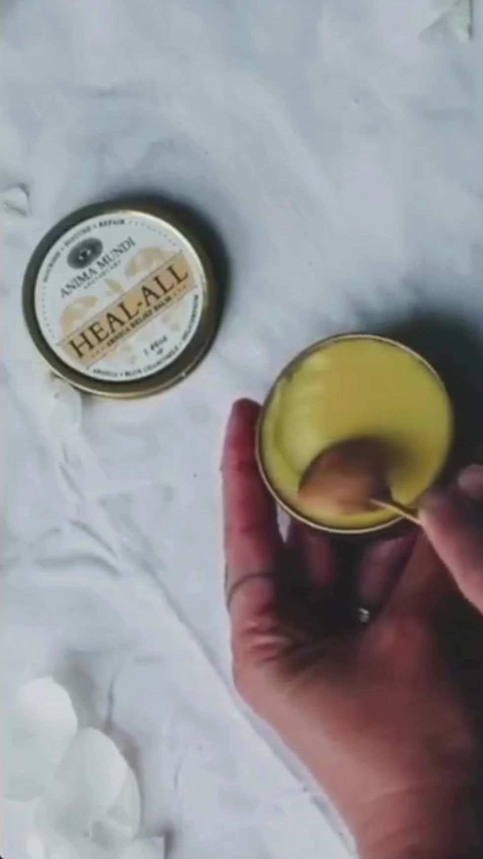 Thumbnail: yellow arnica relief balm in a gold tin with a scoop