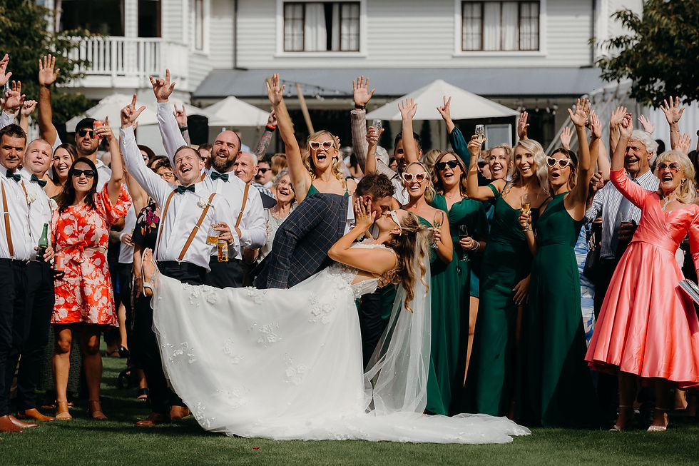 bride and groom kissing with guests celebrating