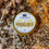 Thumbnail: yellow arnica relief balm in a gold tin on flowers