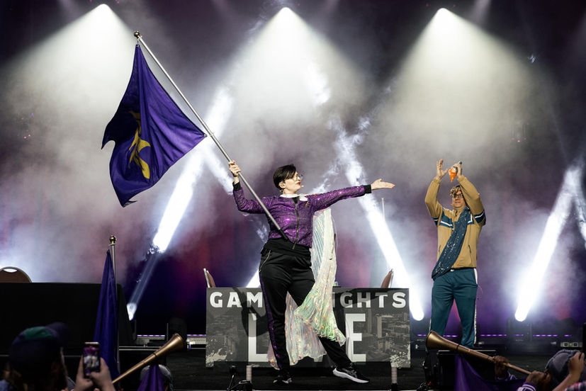 Woman holding a magic the gathering flag on a stage at a MagicCon