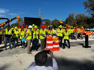 Officials in hard hats gathered around a barrel to sign legislation