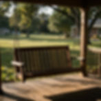 A wooden porch swing on a covered porch, looking out to the lawn and trees