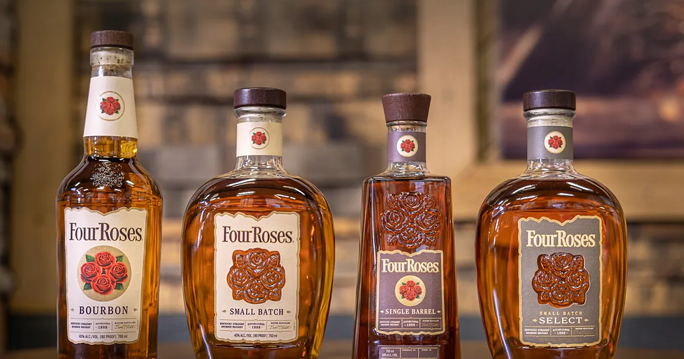 Four Four Roses bourbon bottles on a wooden surface. Labels read Bourbon, Small Batch, Single Barrel, and Small Batch Select. Warm lighting.