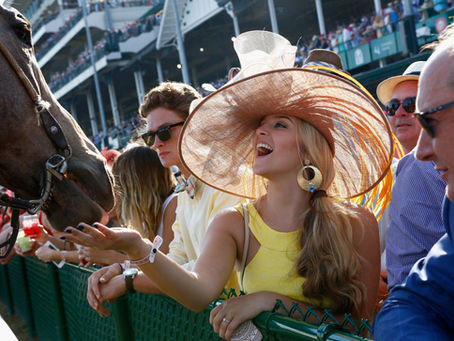blonde woman in yellow dress and wide brimmed hat petting a horse