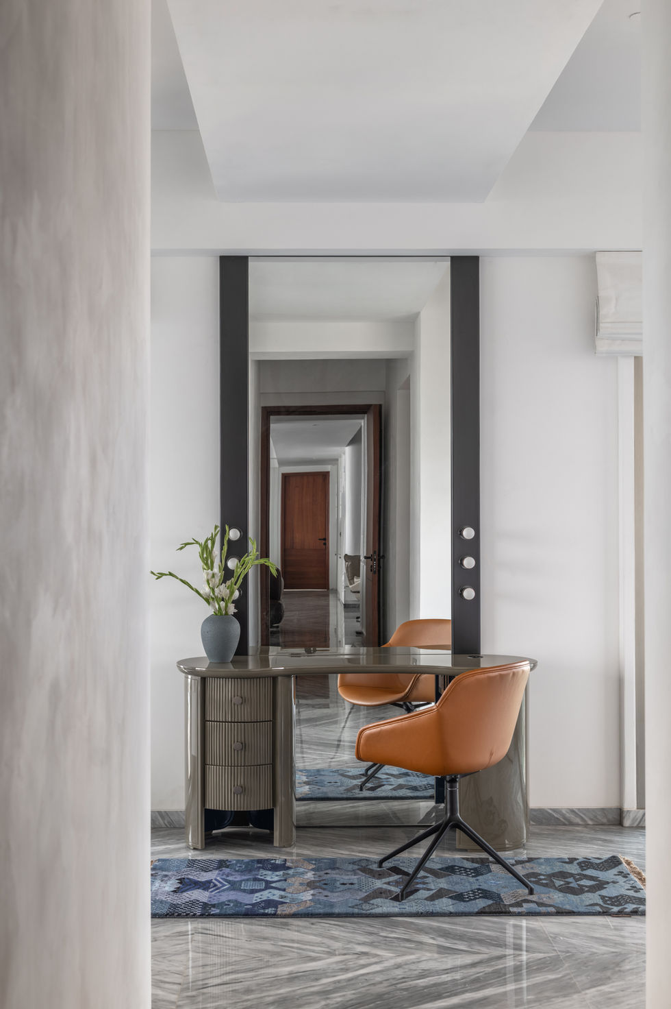 Modern interior with desk, chair, and large mirror.