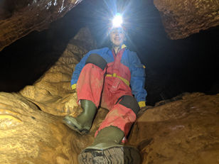 Caving woman sliding through cave.