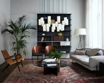Contemporary real estate office lounge featuring bespoke shelving, refined furniture and a black glass relief sofa table, creating an elegant and welcoming professional environment.