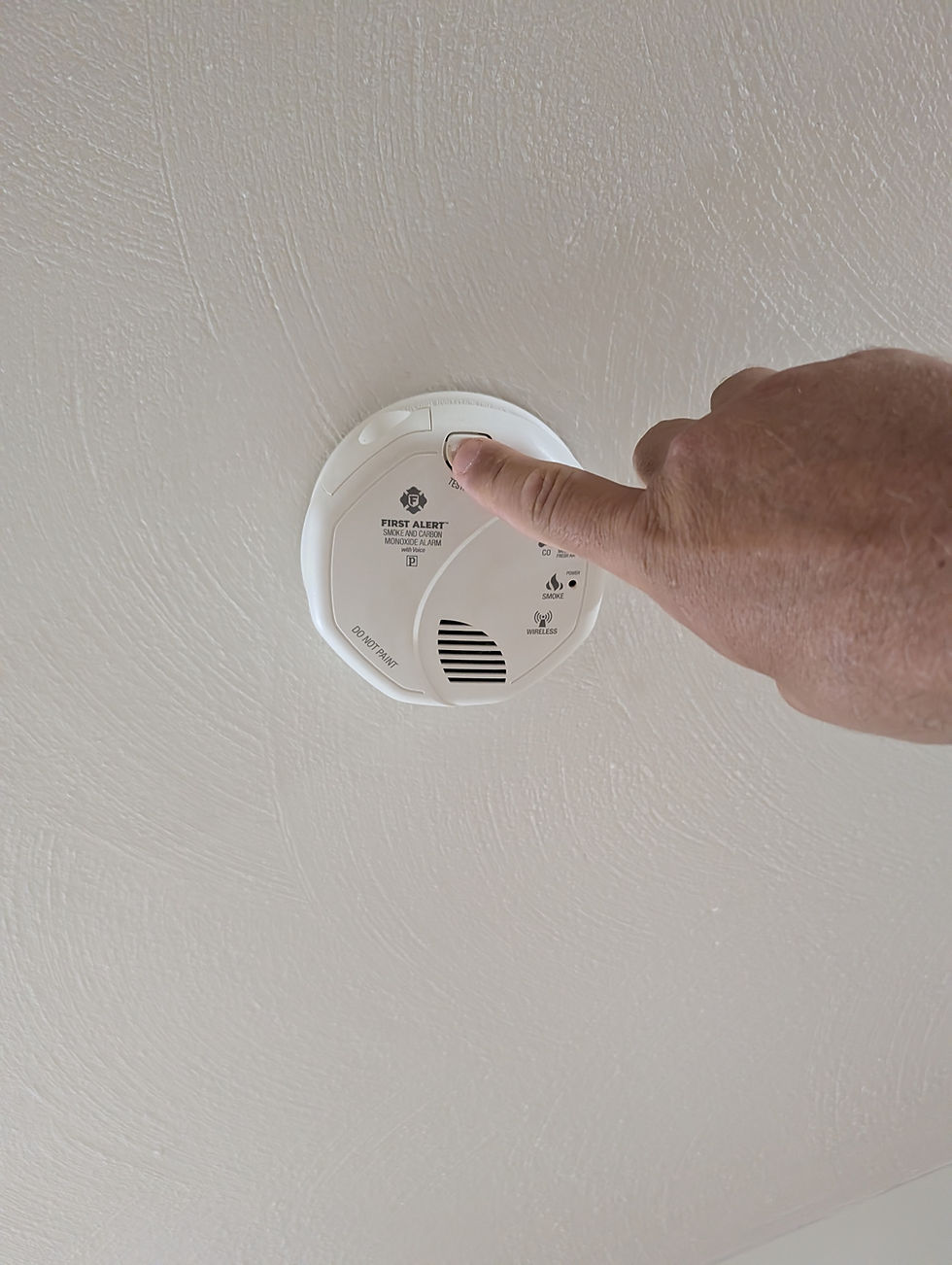 Testing a smoke and carbon monoxide detector as part of fall home maintenance