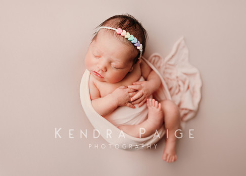 newborn baby wrapped pose with arms and legs resting on tummy