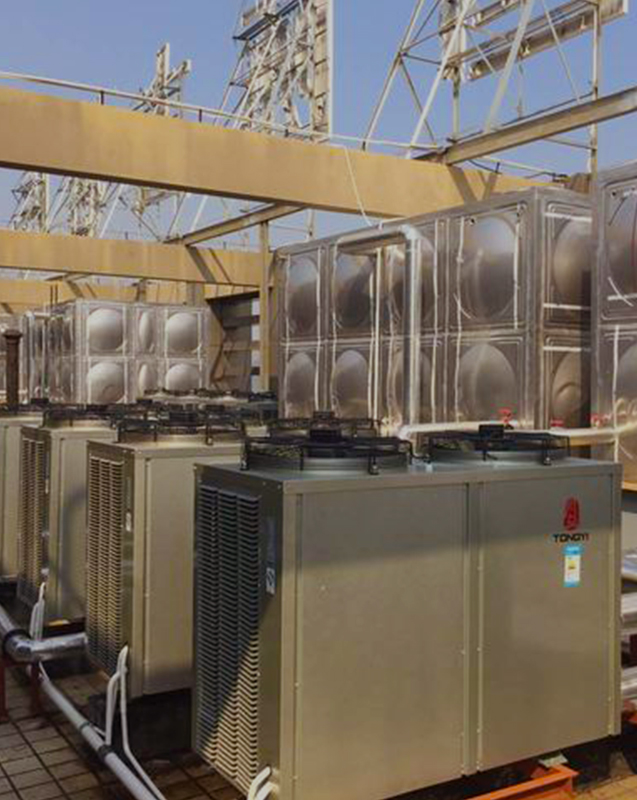 TONGYI's published Wenzhou Zhouyi International Hotel hot-water installation, showing heat-pump units beside water storage tanks