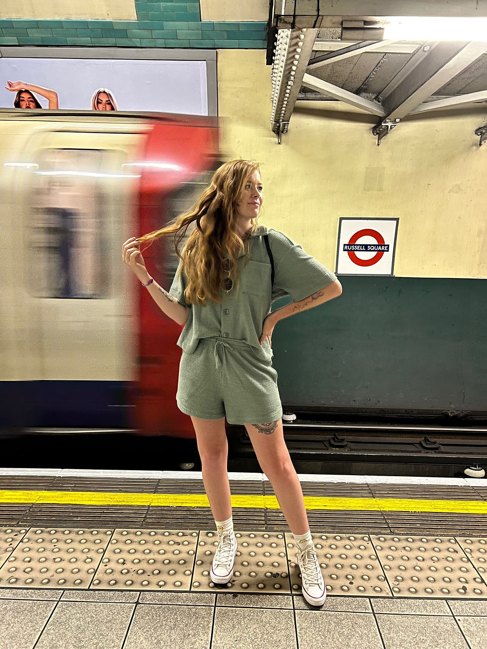 girl standing in front of tube in London wearing green set, holding hair