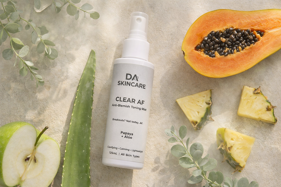 Clear AF anti-blemish toner bottle on a cream stone surface with aloe leaf, papaya, pineapple, green apple and eucalyptus in soft natural light