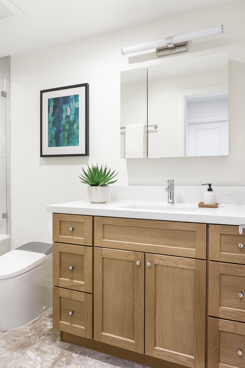 Modern guest bathroom featuring a spacious walk-in shower with a built-in bench, linear drain, and herringbone mosaic floor, paired with a warm wood vanity.