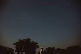 a man in a white hat stands in front of a dark blue sky