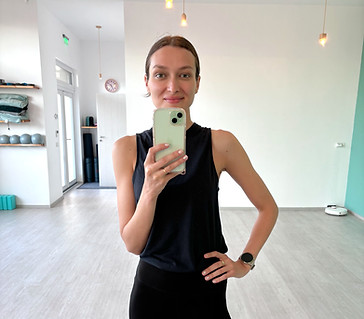 Claudia făcând un selfie în oglinda unui studio de yoga, într-o ținută sport neagră
