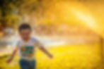 a boy running happily through a shower of water with a sunny yellow background