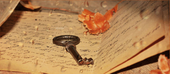 Iron key and orange leaf on an old letter with cursive handwriting.