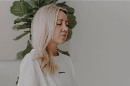 Julia C Woellner sitzt mit geschlossenen Augen im Yoga Sitz