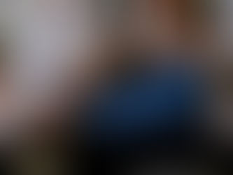 A group of five people, including a man with a beard and glasses in a blue suit, laugh and take a selfie using a sleek white, modern photo booth device outdoors.