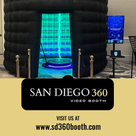 San Diego 360 Video Booth setup featuring a large, black circular inflatable enclosure with a glowing teal and blue LED interior. A 360-degree rotating platform is visible inside, flanked by gold stanchions.