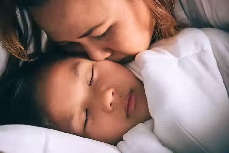 Mae abraçando filha que dorme