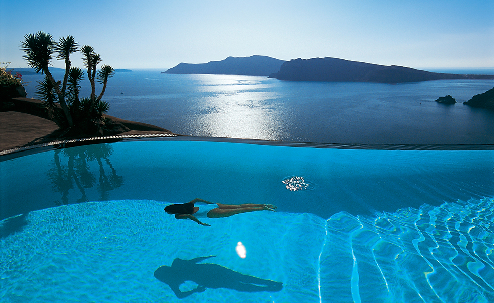 Frau schwimmt in einem Infinity-Pool im Perivolas von Santorin