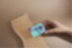 A turquoise acupressure point card is held by a hand, over a wavy-lines-textured tray