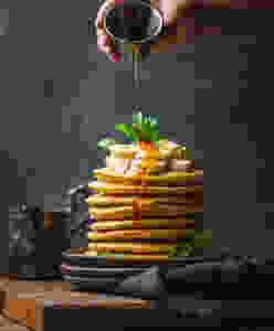 Someone drizzling syrup over potato pancakes
